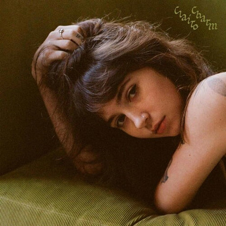 Person with tattoos lying on a green surface, wearing a dark top.
