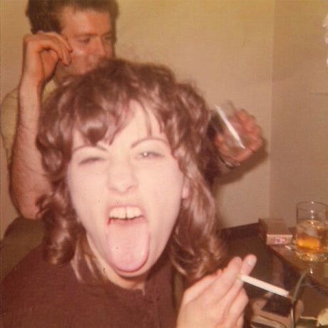 Person with long hair sticking out of another person's hair, with a glass and candle in the background.