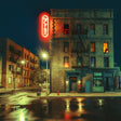 Neon sign on a building at night with reflections on the wet street