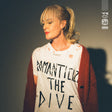 Person wearing a shirt with text, standing against a dark background
