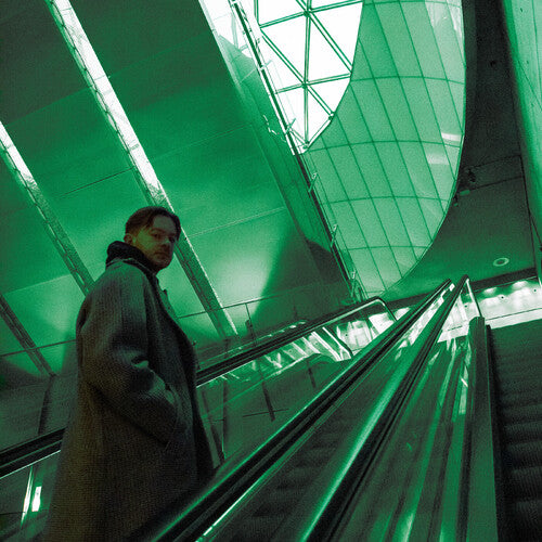 Person standing on an escalator with a green tinted ceiling