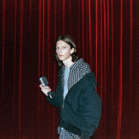 Person holding a microphone in front of a red curtain
