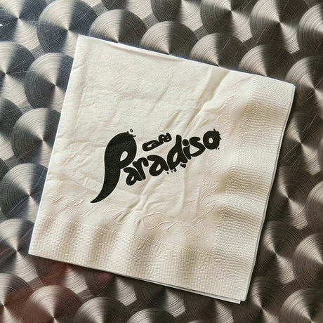 Beige napkin with 'Cafe Paradiso' text on a textured surface