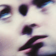 An abstract, heavily blurred close-up of a human face with soft purple, pink, and dark shadow tones.