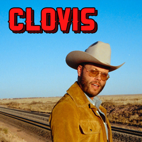 A man wearing a light beige cowboy hat, yellow-brown suede jacket, and gold-tinted sunglasses stands beside railroad tracks in an open desert landscape under a clear blue sky. Large red text reading 'CLOVIS' appears at the top left.