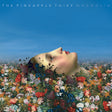 Album cover art for 'The Pineapple Thief Magnolia' featuring a surreal scene of a woman's face emerging from a dense field of colorful flowers under a clear blue sky.