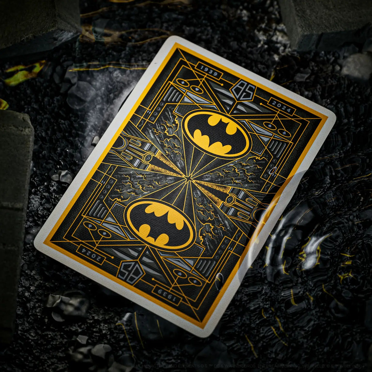 Playing card with Batman logo on a dark, rocky surface