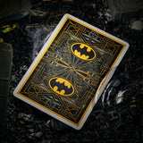 Playing card with Batman logo on a dark, rocky surface