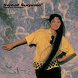 Album cover with a person in a yellow shirt and black pants against a textured background, featuring the text 'Sweet Surprise' and 'Tamlyn Tomita'.
