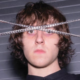 Person with chains over their eyes against a gray background