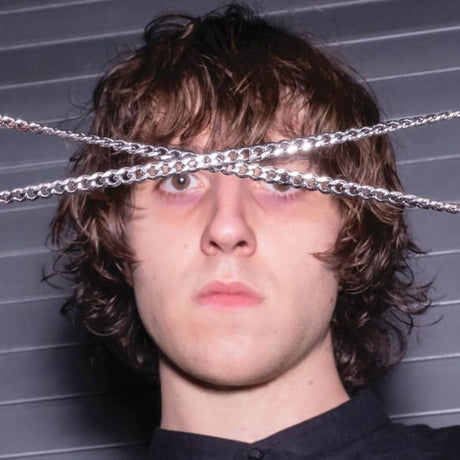 Person with chains over their eyes against a gray background