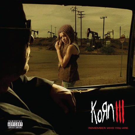 Korn III - Remember Who You Are album cover art, featuring a woman standing outside a car window while a man sits inside in silhouette. Oil pumps are visible in the background under a sepia sky.