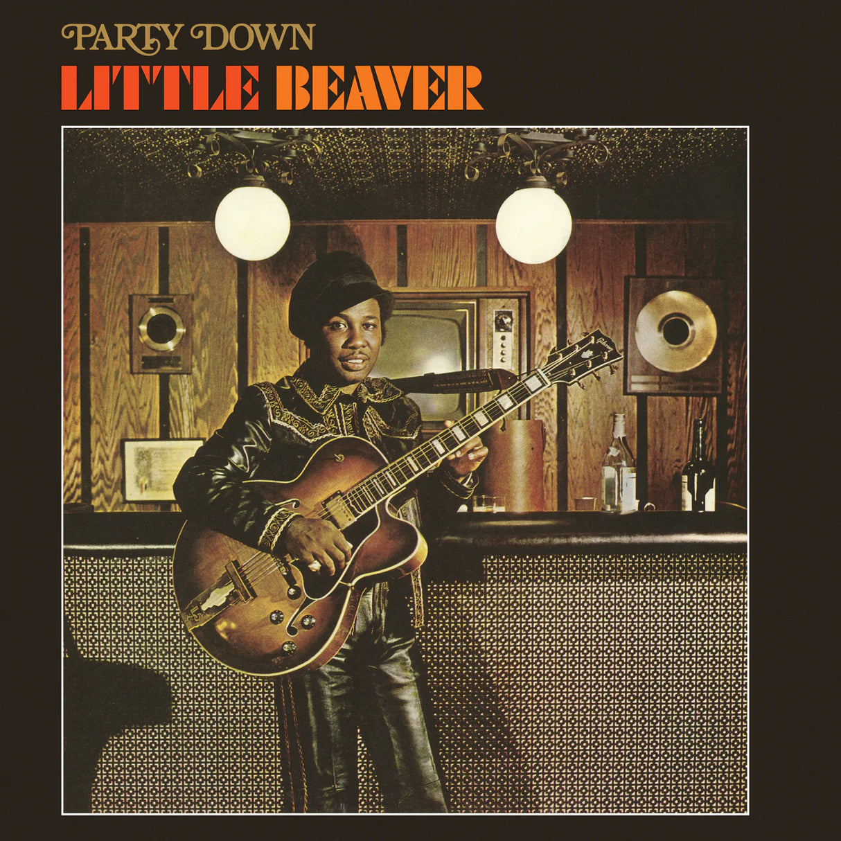 Album cover featuring a person playing guitar in a room with wood paneling and a television.