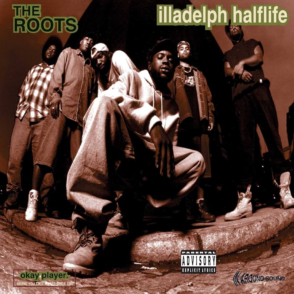 Album cover for 'illadelph halftime' by The Roots featuring a group of people on a street.