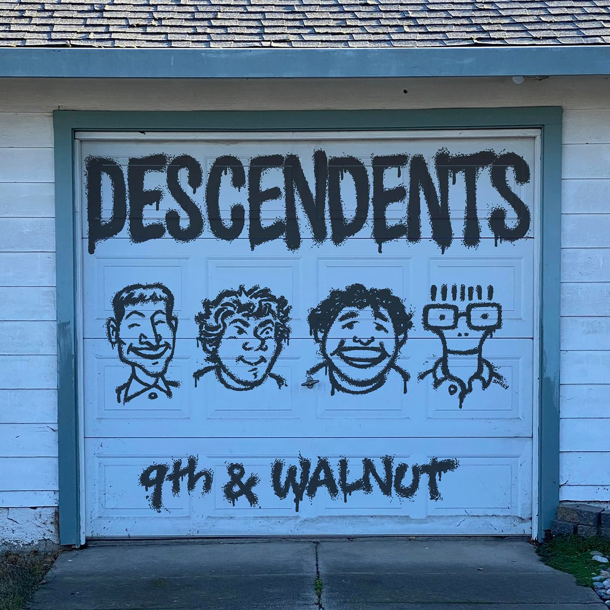Garage door with 'DESCENDENTS 9th & WALNUT' spray-painted on it.