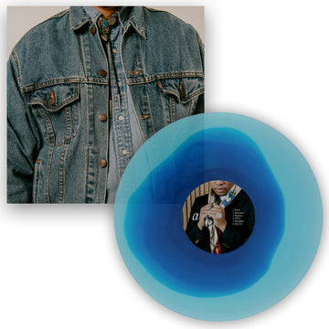 Blue vinyl record with a person's face on it, next to a denim jacket.