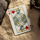 Playing card with a cowboy holding a gun on a textured surface