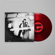 Red vinyl record with a black and white album cover featuring people, on a light gray background.