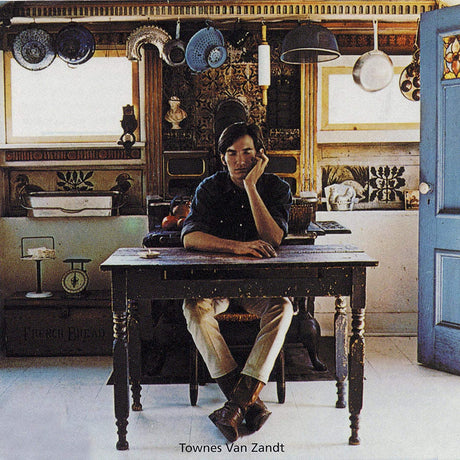 Person sitting at a desk in a room with decorative elements and a blue door.