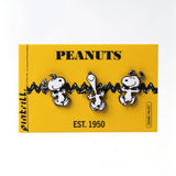 Three Snoopy enamel pins displayed on a yellow Peanuts brand backing card against a white background.