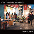 Album cover for Brian Eno's 'Another Day on Earth' featuring a photograph of a bustling Chinese street market at dusk, framed by black borders with white text.