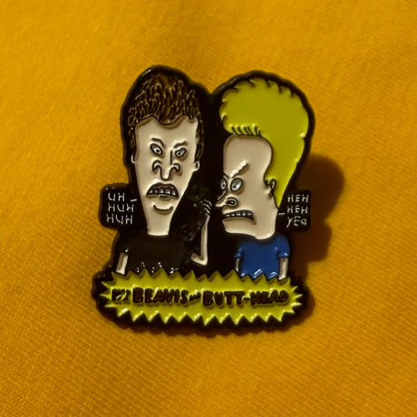 Metallic badge with two characters from a popular TV show on an orange background