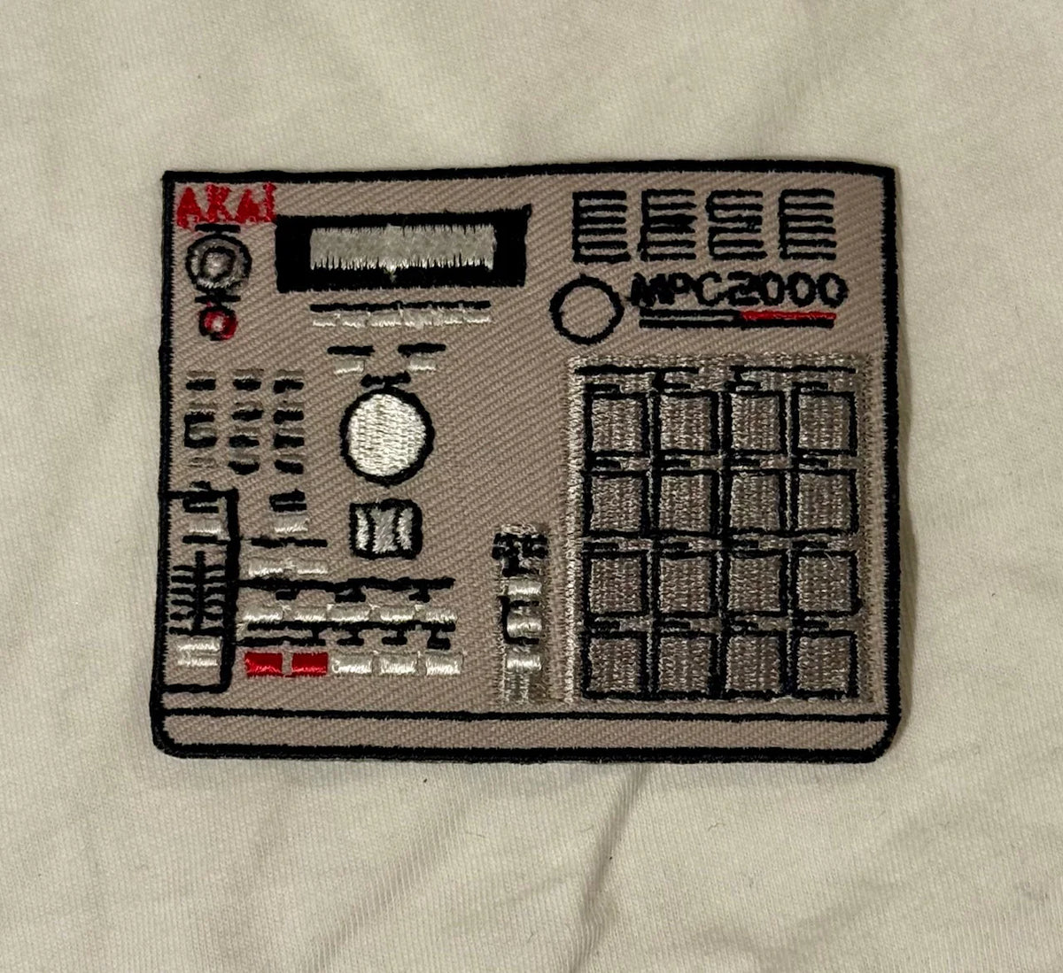Embroidered patch of a music synthesizer on a beige fabric background