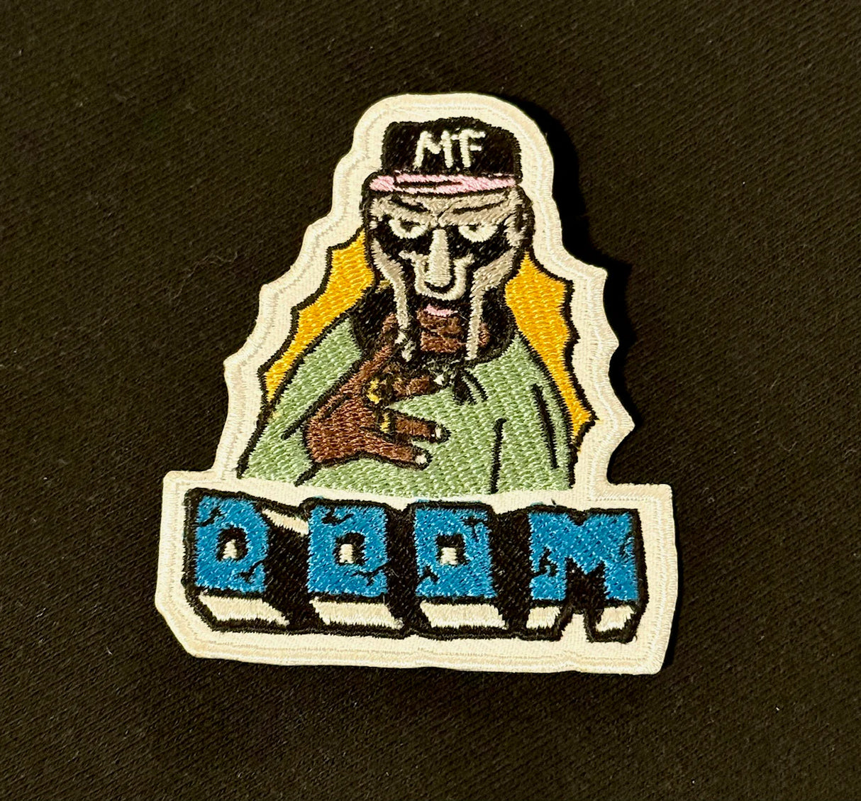 Embroidered patch with a character wearing a cap and holding a gun, with 'DOOM' text below on a black background.