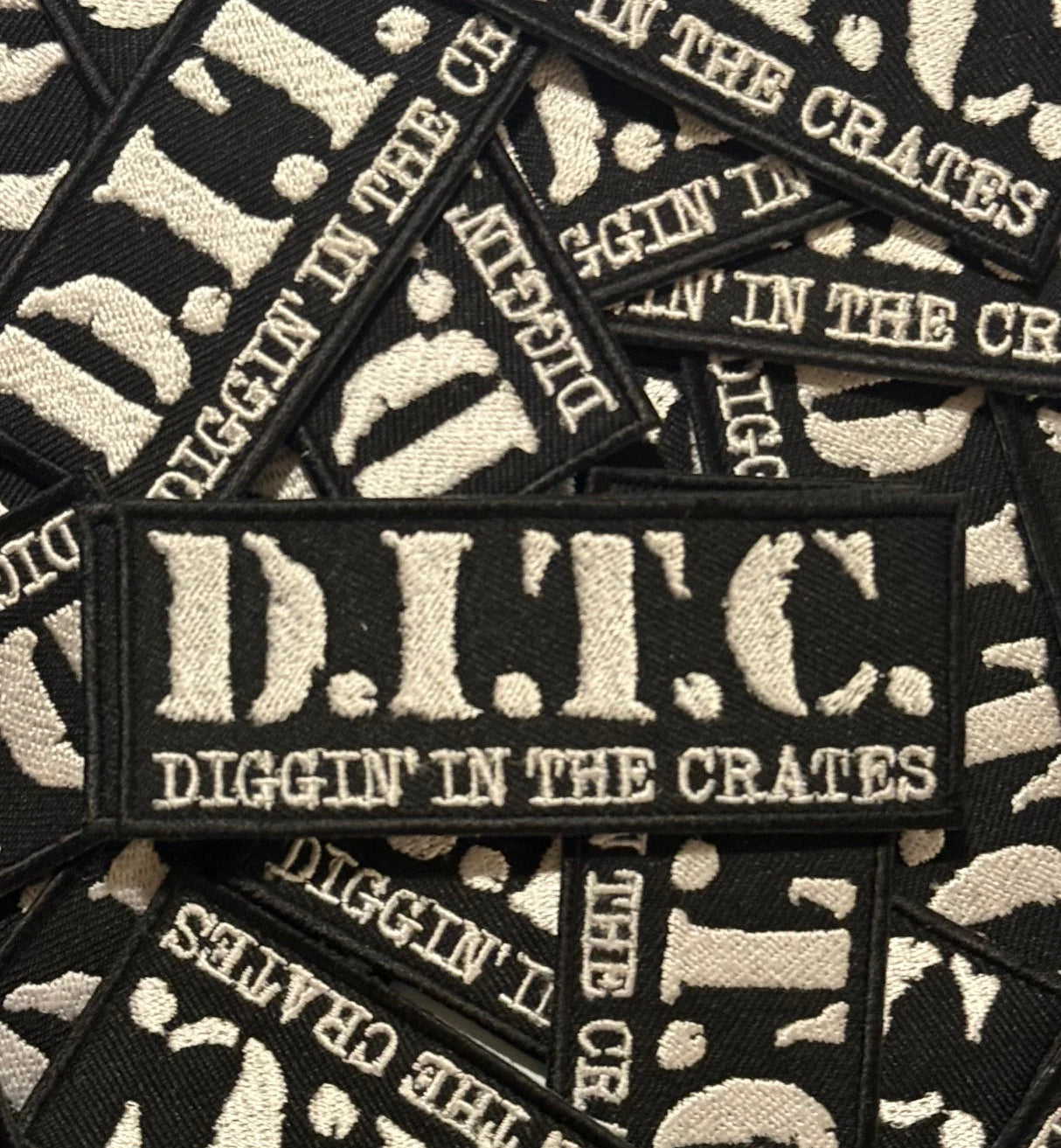 Black and white patches with 'D.I.T.C. Diggin' in the Crates' text on a pile of similar patches.