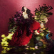 Woman in a red dress surrounded by flowers against a pink background