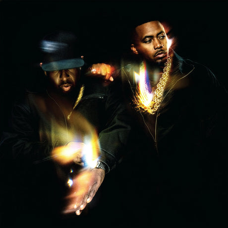 Two men with gold chains and dark clothing against a black background