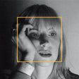 Black and white portrait of a person with a gold border, with a blurred background.
