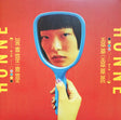 Person holding a blue mirror reflecting their face against a red background with text.