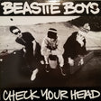 Album cover of 'Check Your Head' by Beastie Boys featuring three members sitting outdoors.