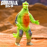 Toy figure of Godzilla on a textured orange surface with 'GODZILLA' branding.