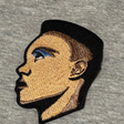 Embroidered patch of a person's profile on a gray fabric background