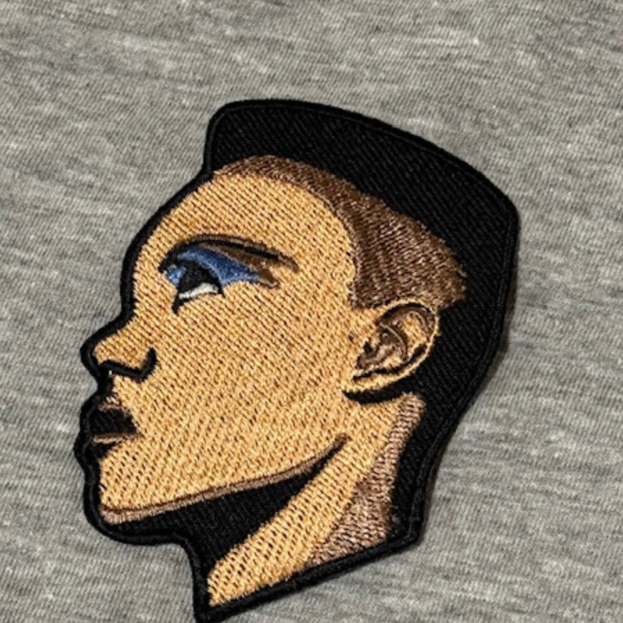 Embroidered patch of a person's profile on a gray fabric background