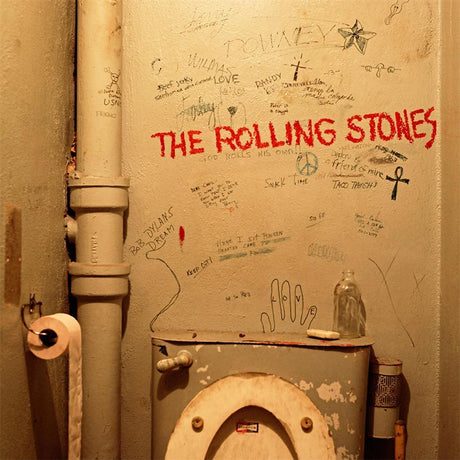 Toilet with 'The Rolling Stones' graffiti on a wall with various writings and drawings.