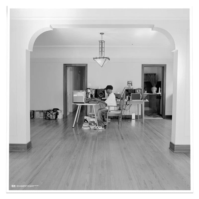 Person sitting at a desk in a room with a chandelier and wooden floor.