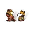 Two Snoopy and Woodstock enamel pins on a white background, one showing Woodstock in a brown outfit and the other showing Snoopy in a yellow striped sweater.