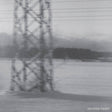 Black and white photograph of a large electricity pylon standing in a snowy landscape, with a line of trees in the background and the text 'tacoma radar' in the bottom right corner.