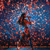 Person on stage with confetti falling around, against a dark blue background