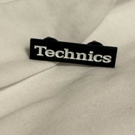 Black Technics logo on a beige fabric background
