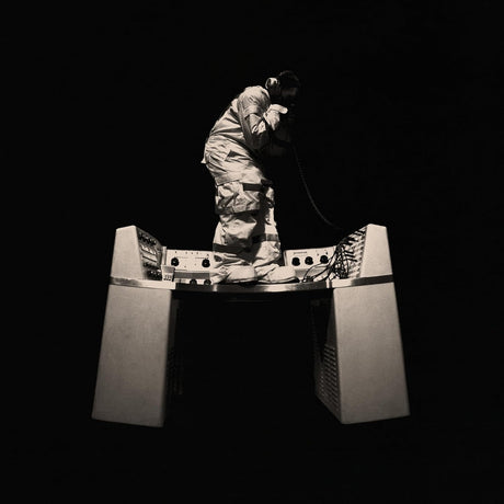 Person in a reflective suit with a helmet on a stand against a black background