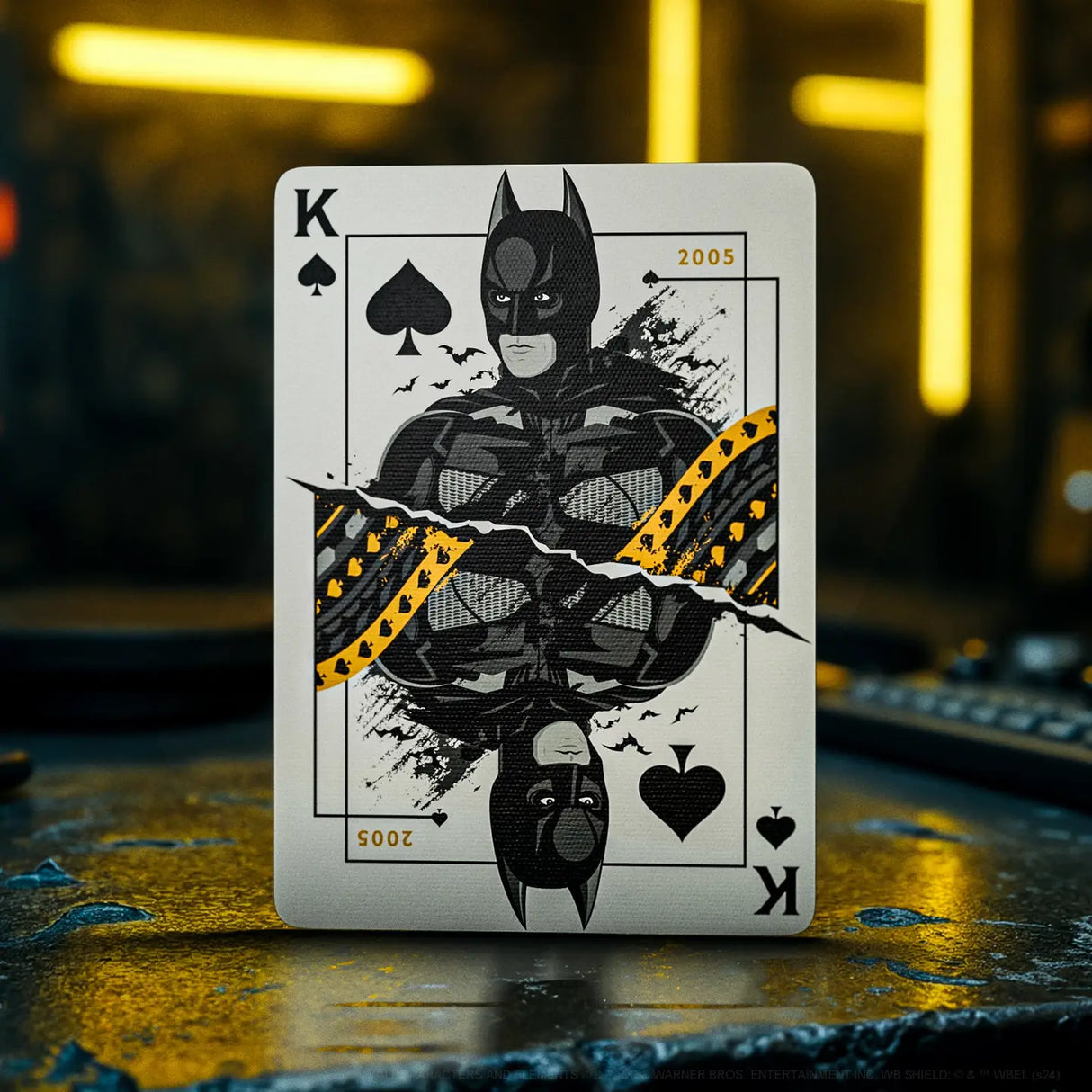 Playing card with a superhero design on a dark surface with blurred lights in the background