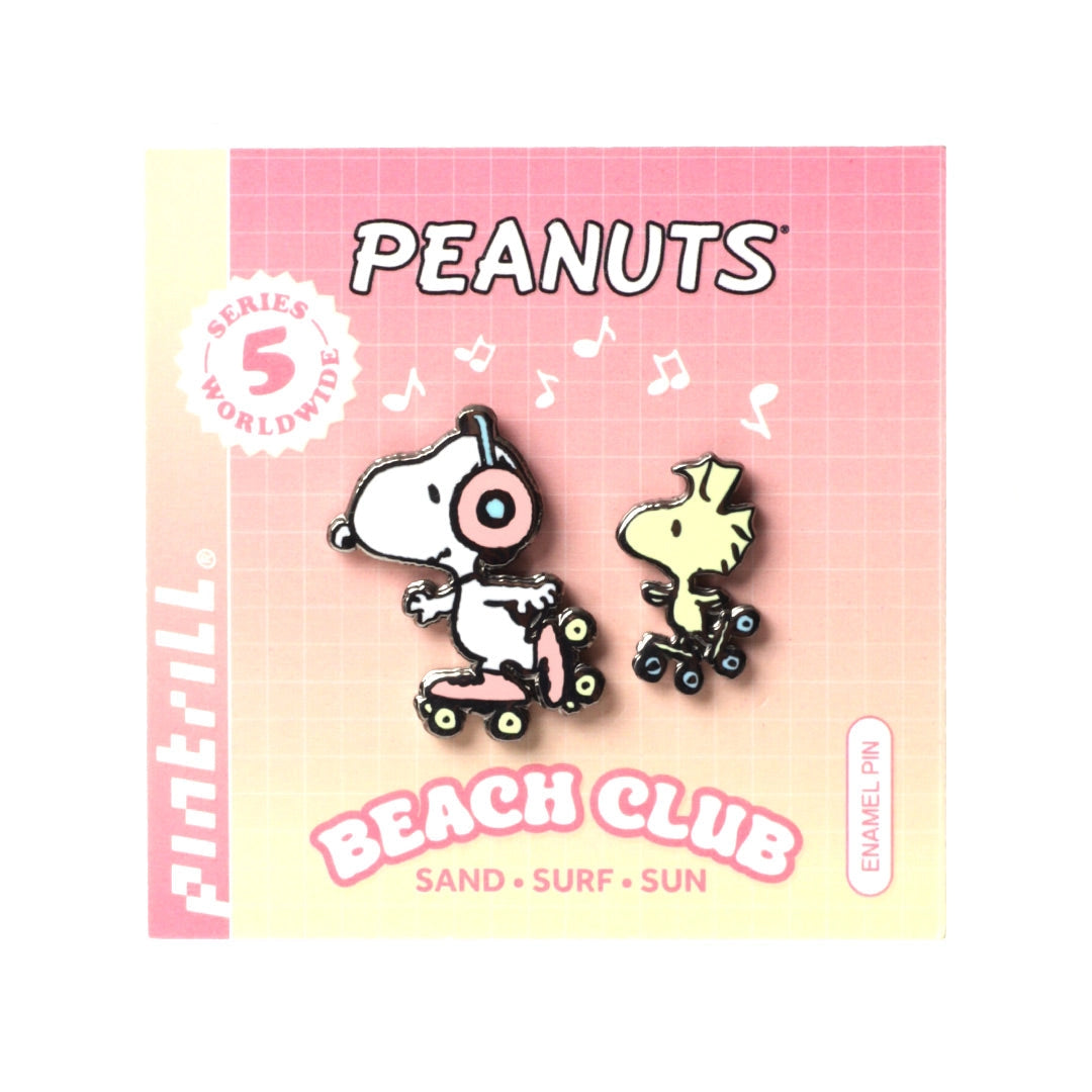 Two enamel pins of cartoon characters on a 'Peanuts' Beach Club packaging with a pink and yellow gradient.