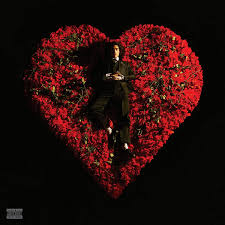 Person in a suit sitting on a heart-shaped arrangement of red roses against a black background