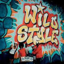People sitting in front of a colorful mural with 'Wild Style' text