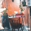 Wooden table with books and a chair in a room with a plant and a mirror.