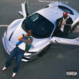 Two people interacting with a futuristic vehicle on a road, with a 'Parental Advisory Explicit Content' label.